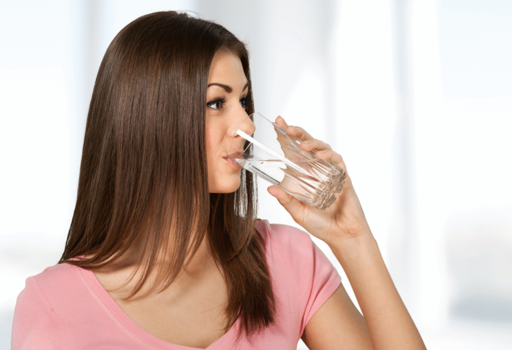 Frau trinkt Wasser aus einem Glas zuhause