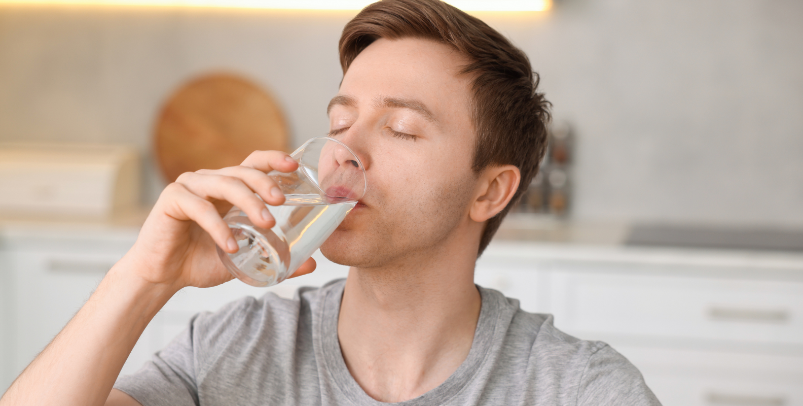 Ein Mann trinkt Wasser aus einem Glas.